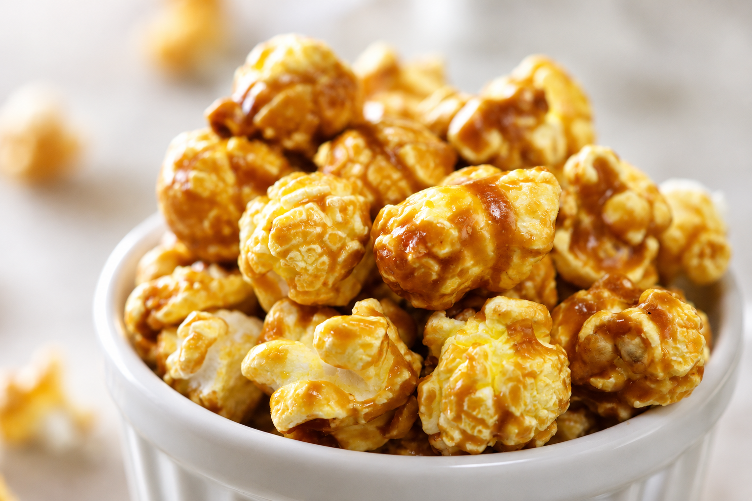 Golden brown, decadent caramel popcorn sitting in a white bowl